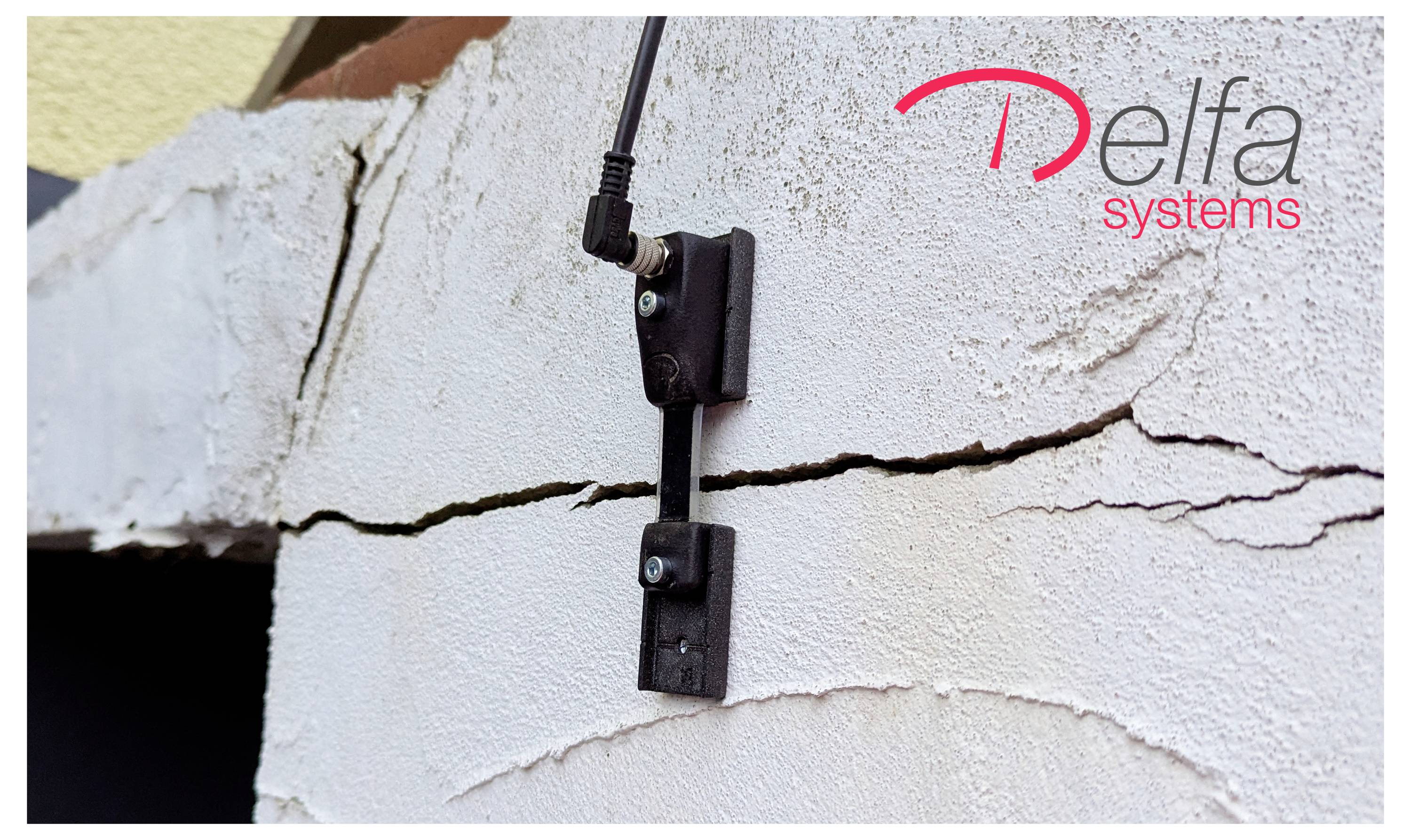 Een aan de muur bevestigde elektronische sensor met een kabel is bevestigd aan een gescheurde oppervlakte. De afbeelding heeft het logo 'Delfa Systems' in de hoek.