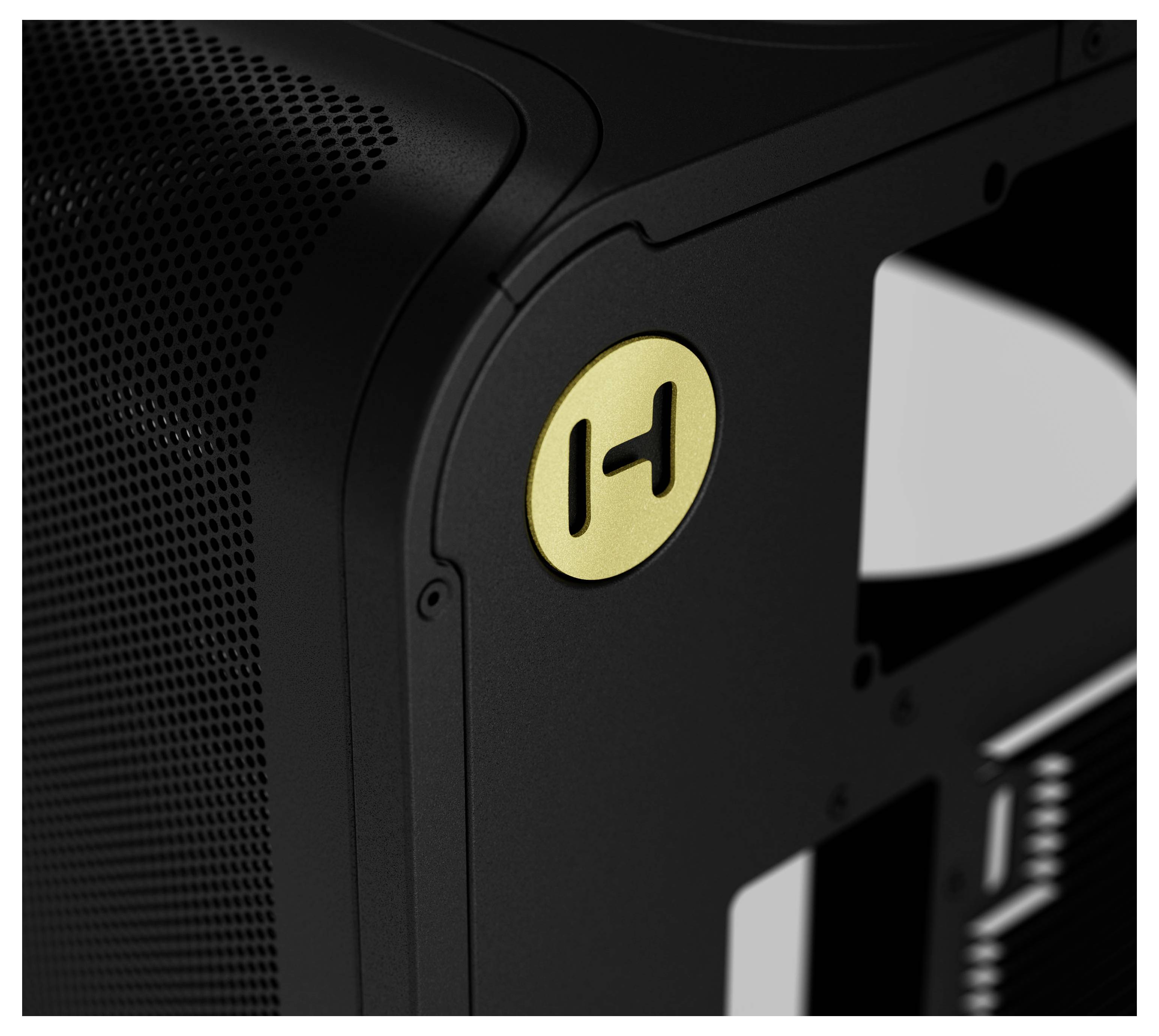 Een close-up van een slanke zwarte apparaat met een gedetailleerd meshontwerp en een circulair gouden embleem met een gestileerde 'H'.