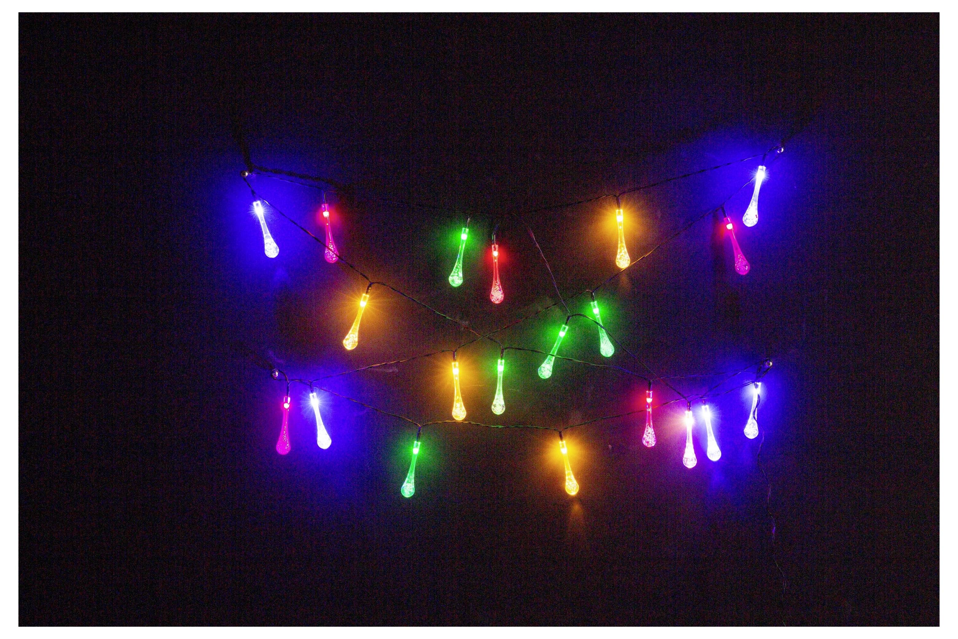 Kleurrijke slingers met verlichting hangen tegen een donkere achtergrond, met lampjes in rode, groene, blauwe, roze en gele tinten.
