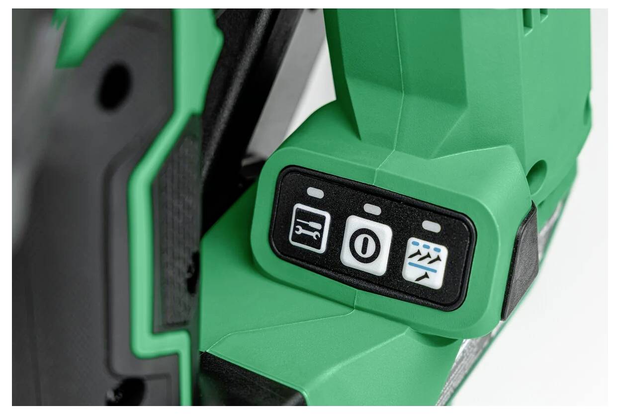 Close-up van het bedieningspaneel van een groene powertools met drie knoppen: een afbeelding van een zaagblad, een schijf met een schuine streep erdoor, en gestileerde golven.