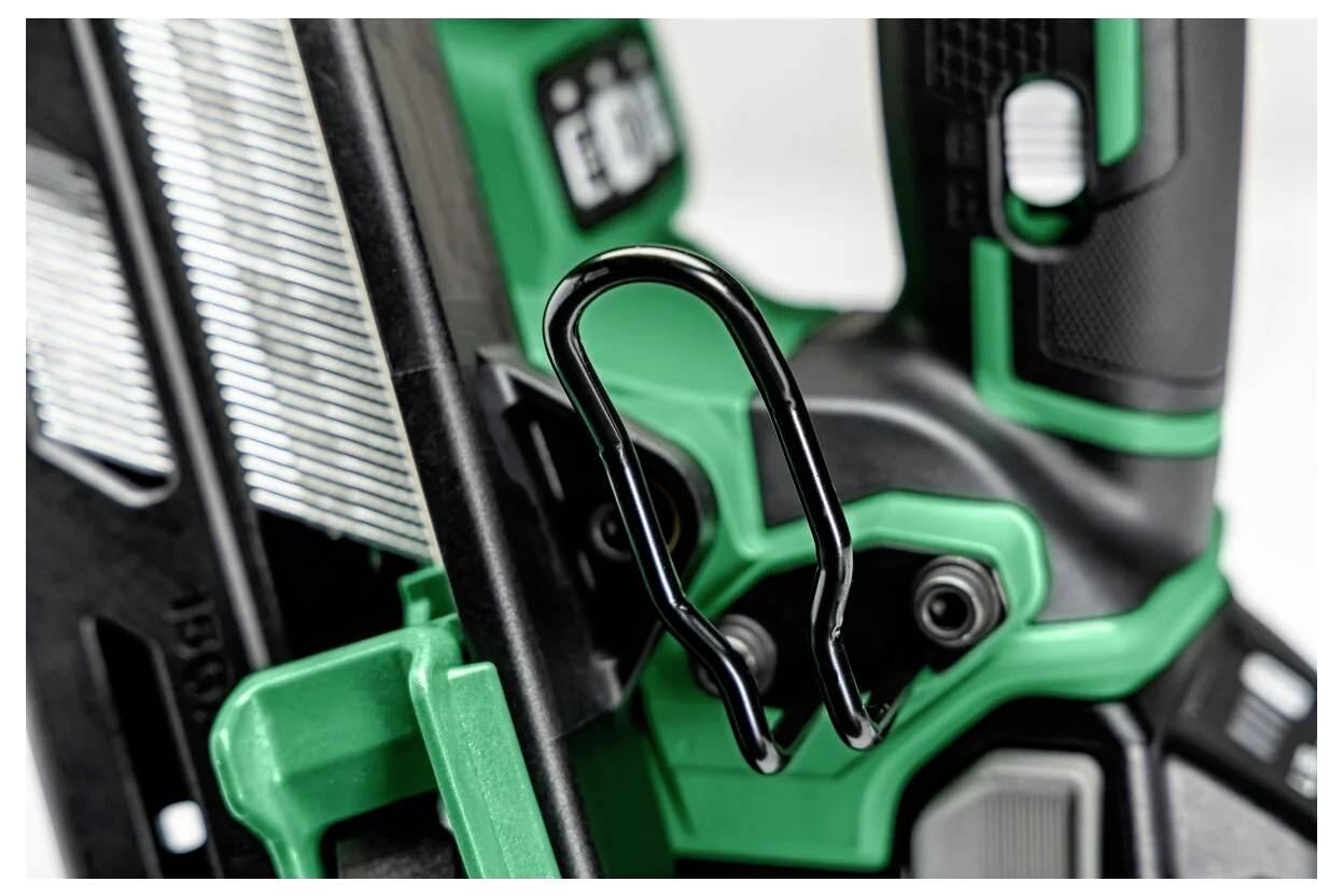 Close-up van een groene en zwarte gereedschapsmachine met een metalen veiligheidshaak, waarbij een deel van de greep en de gestructureerde oppervlakken zichtbaar zijn.