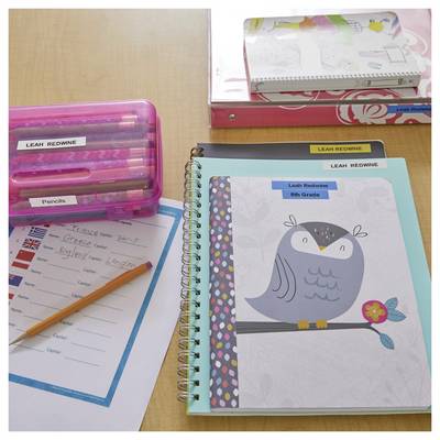 Een bureau met schoolspullen, inclusief een etui, schriften gelabeld met 'Leah Redwine', en een papier met de titel 'Reisplan naar Engeland'.
