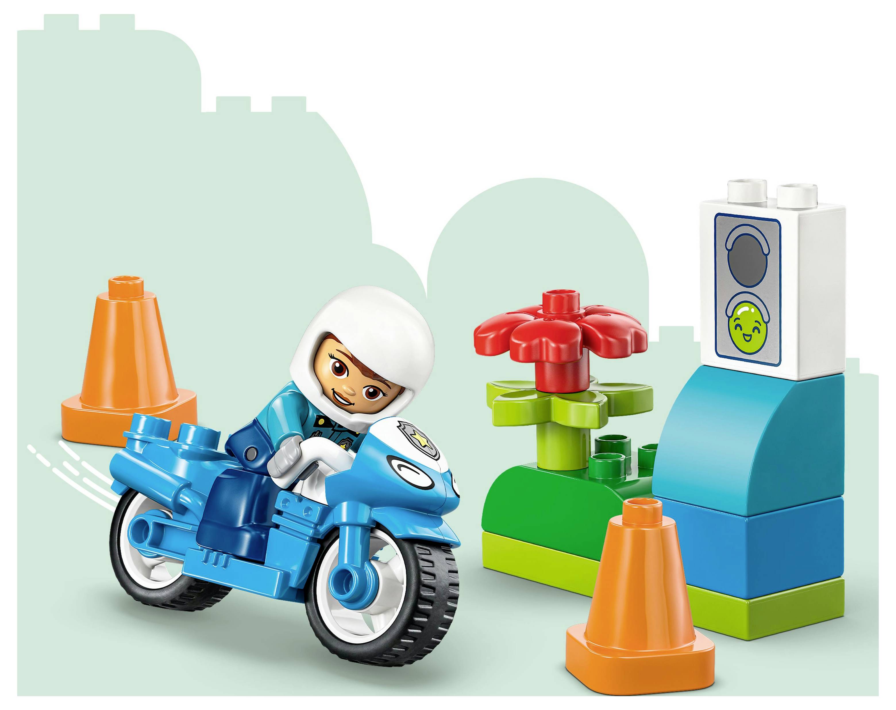 Een poppetje van een kind in het blauw rijdt op een speelgoedmotor tussen oranje pionnen door, langs kleurrijke blokken inclusief een rode bloem en een lachend gezicht.