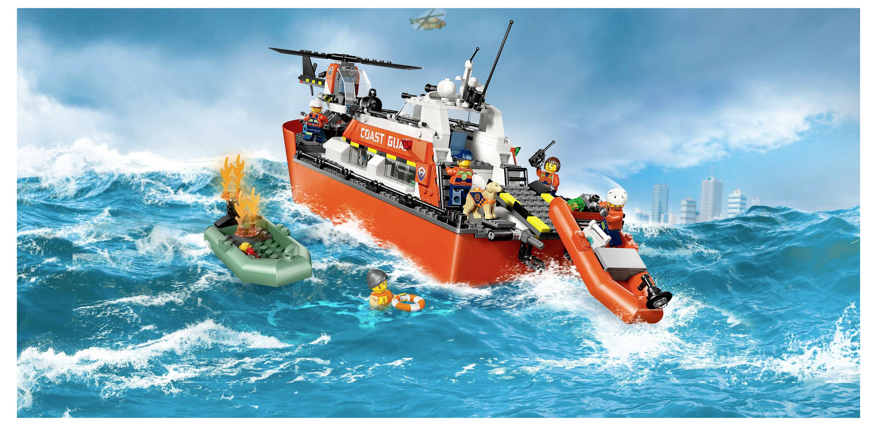 Een kustwachtmodellenschip in woelige zee met een helikopter erboven. Bemanningsleden redden een persoon uit een reddingsboot met behulp van een opblaasbare reddingsboot.