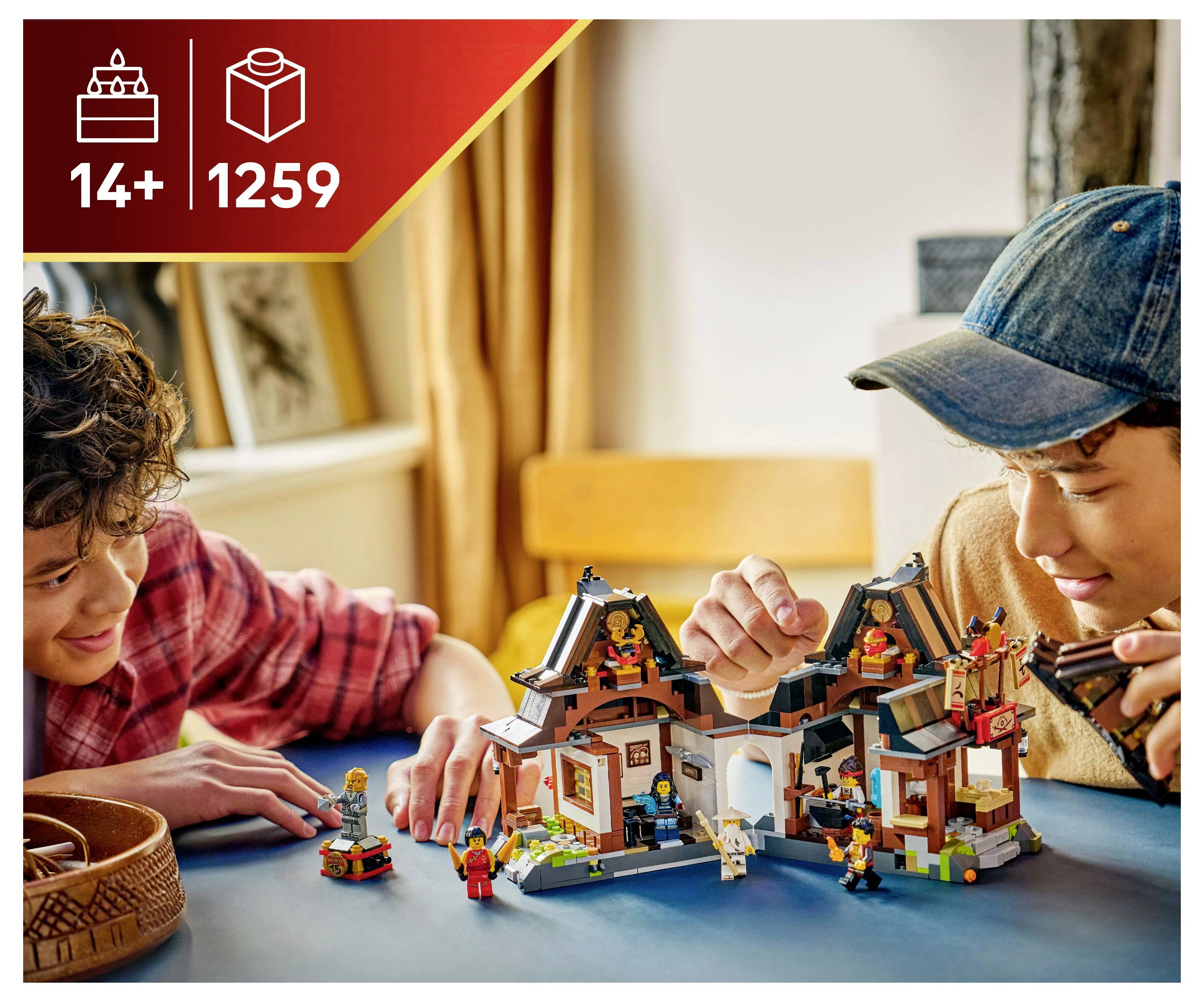 Twee mensen bouwen enthousiast en spelen met een gedetailleerde LEGO-set in Aziatische stijl aan een blauwe tafel. De doos toont '14+' en '1259' onderdelen.