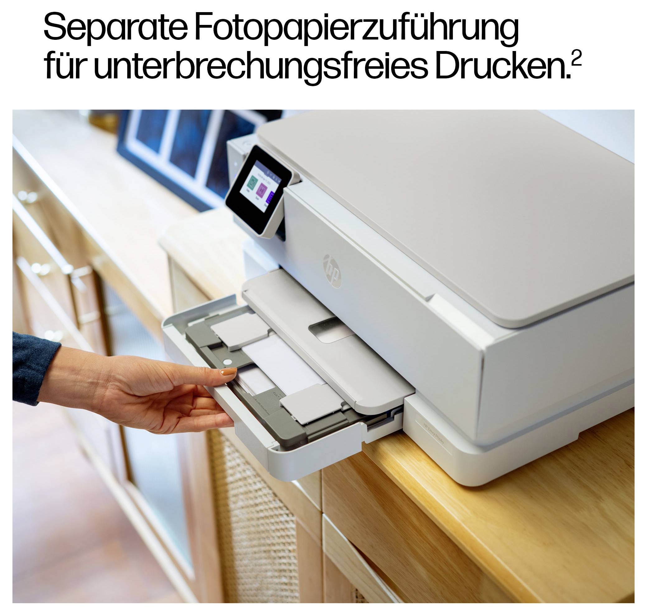 Een persoon plaatst fotopapier in een printerlade op een houten aanrecht. De printer heeft een digitaal display. Tekst boven luidt 'Separate invoer voor fotopapier voor ononderbroken printen'.