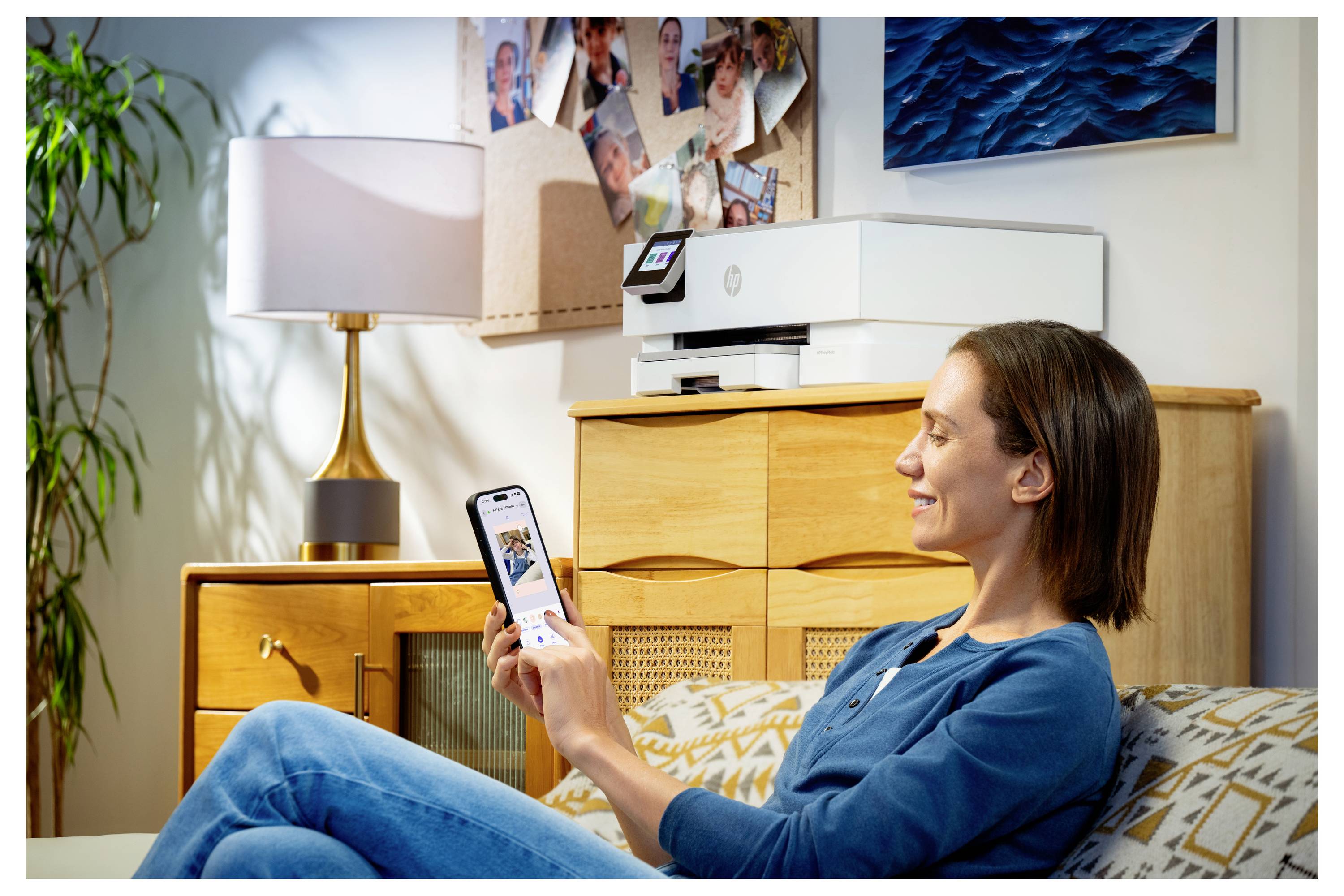 Een persoon zit op een bank terwijl hij een smartphone gebruikt, met een printer op een houten kast op de achtergrond, waardoor een gezellige woonkamerscène wordt gecreëerd.