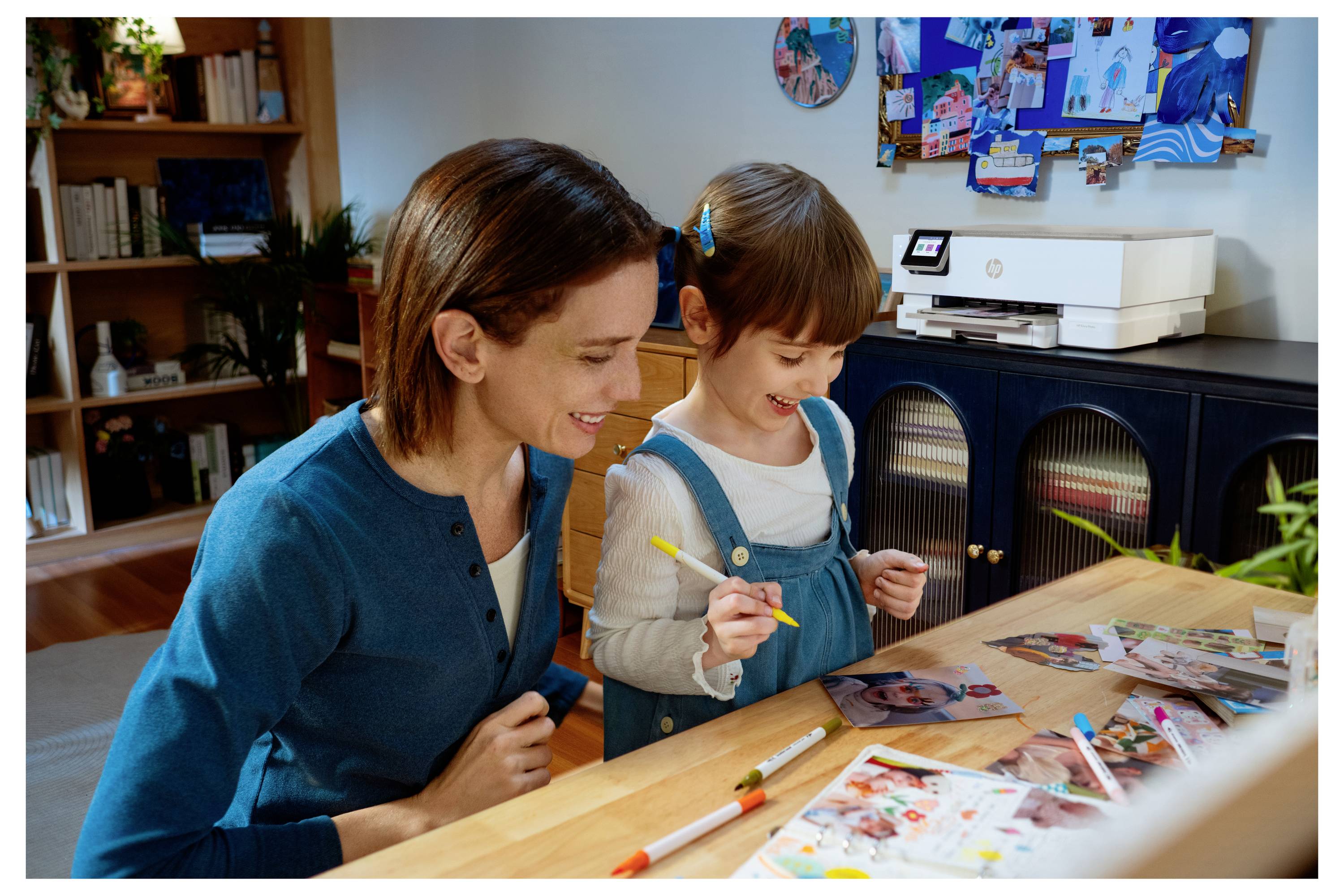 Een moeder en dochter zitten samen gezellig te knutselen aan een houten tafel, omringd door knutselspullen en foto's, in een gezellige kamer vol boeken.