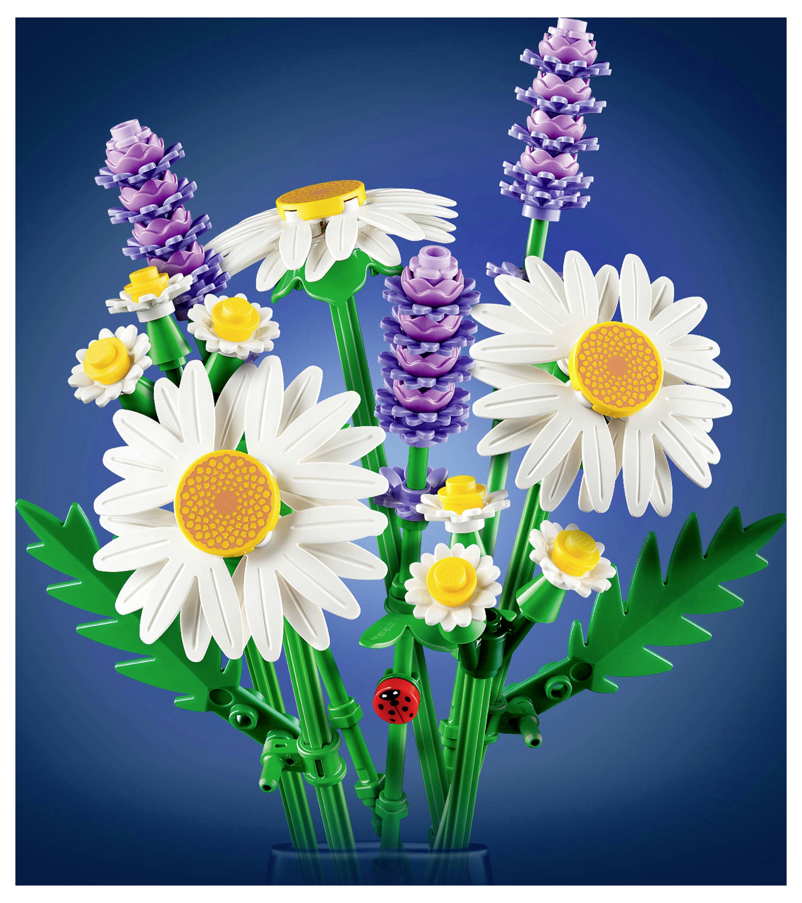 Een kleurrijk boeket samengesteld uit speelgoed bouwblokken, met witte madeliefjes, kleine gele bloemen, paarse bloemen en groene bladeren.