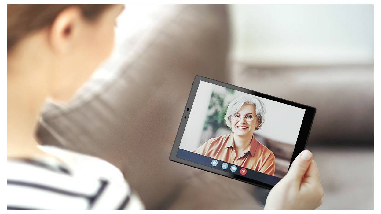 Een persoon houdt een tablet vast en voert een videogesprek met een andere persoon. Het scherm toont een oudere volwassene met grijs haar, die warm glimlacht.