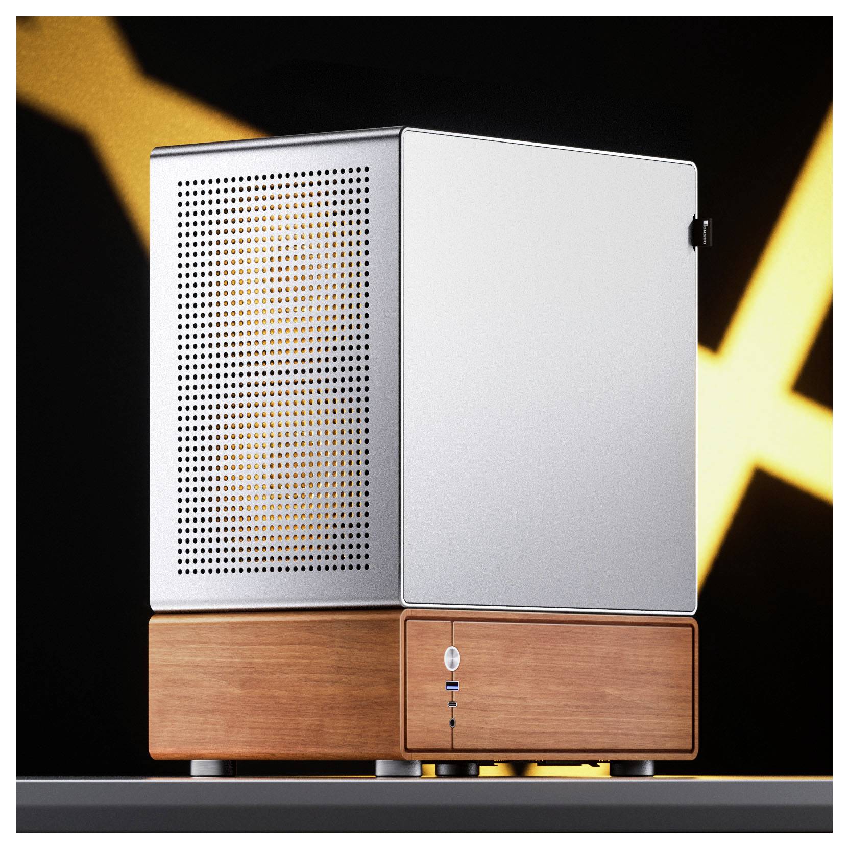 Een kleine, moderne desktopcomputer met een strak metalen afwerking en een houten basis staat op een grijze ondergrond tegen een wazig zwart en geel achtergrond.
