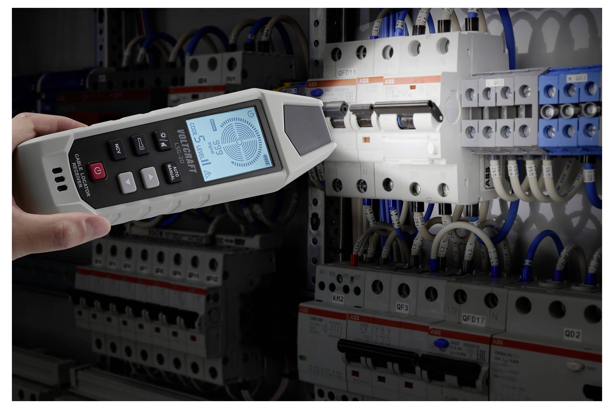 Een hand houdt een digitale elektricische tester dicht bij een stroomkastpaneel. Het scherm van de tester geeft aflezingen weer, wat aangeeft dat spanning aanwezig is.