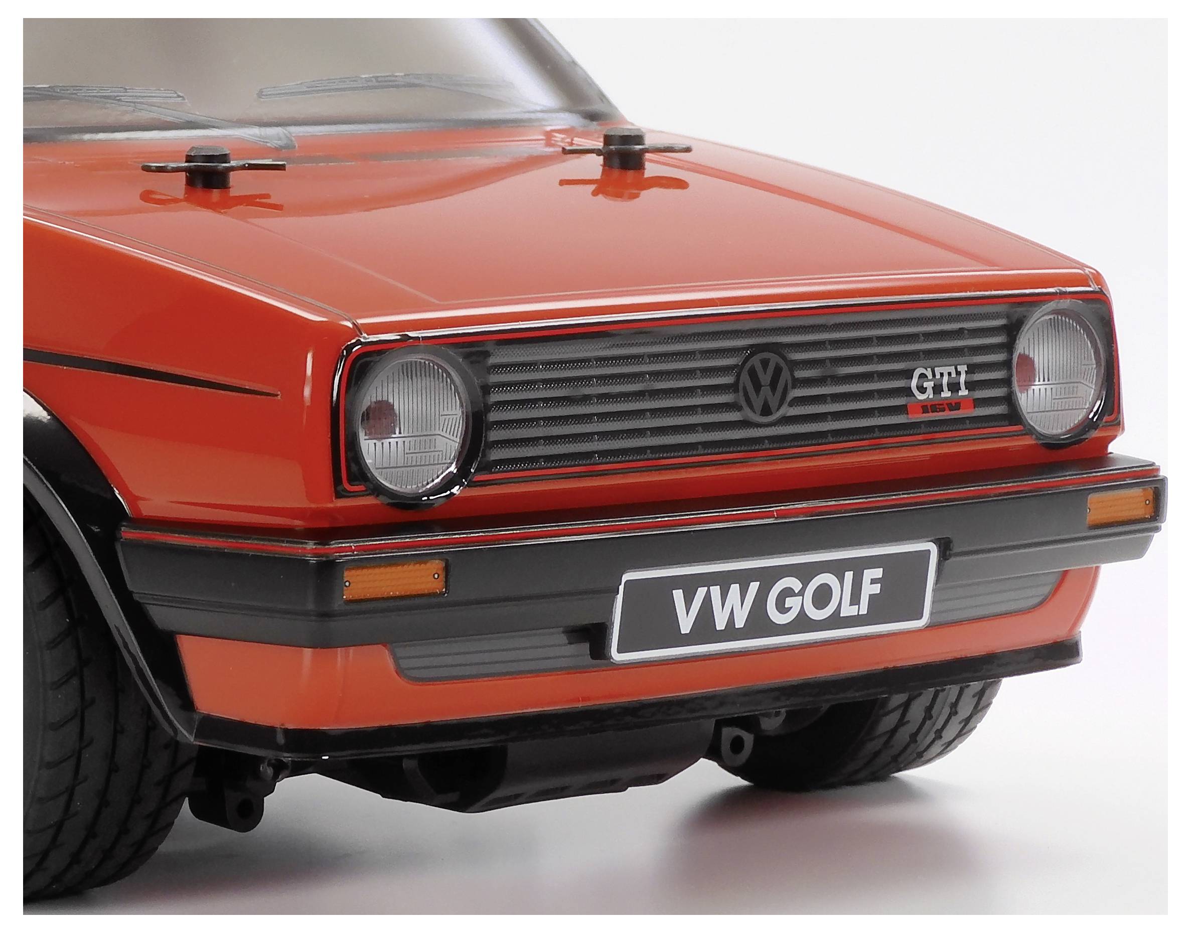 'Vooraanzicht van een rode vintage VW Golf GTI modelauto, met kenmerkende ronde koplampen en een klassieke grille, op een witte achtergrond.'