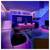Een moderne woonkamer en keuken met neonverlichting in roze en blauwe tinten, met een trap, twee stoelen en een kleine glazen tafel.