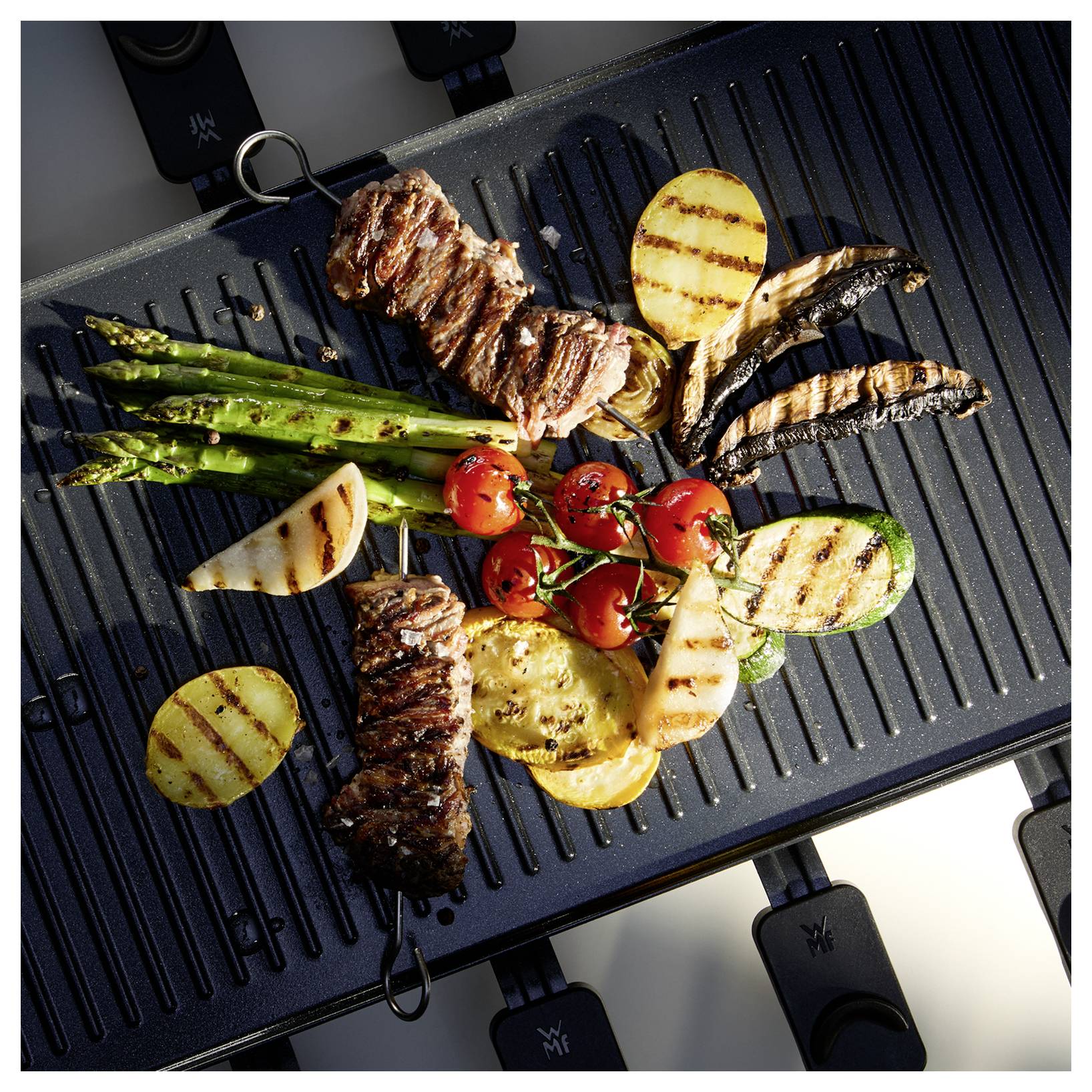 Gegrilde groenten en biefstuk op een grillpan met daarin asperges, kerstomaten en paprika's, waarbij een verscheidenheid aan kleuren en texturen wordt tentoongespreid.