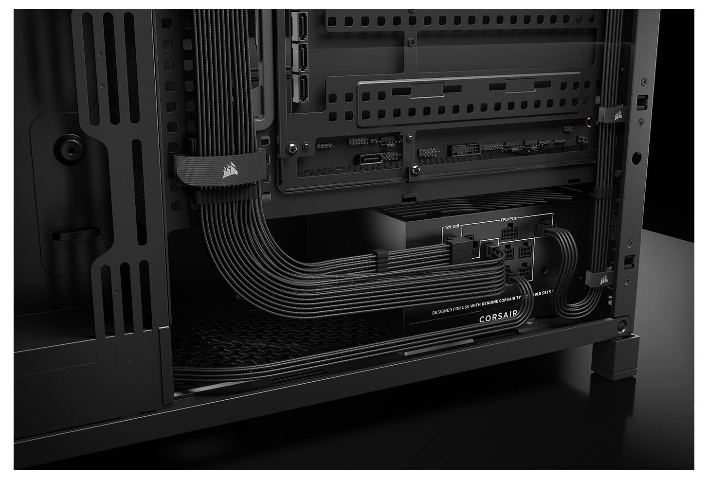 'Achterkant van een computerbehuizing met netjes georganiseerde kabels aangesloten op voeding en moederbord. Corsair-logo zichtbaar op componenten.'