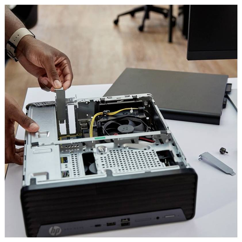 Een persoon is een desktopcomputer aan het upgraden of repareren, met de focus op het verwijderen of installeren van een onderdeel in een computerkast.