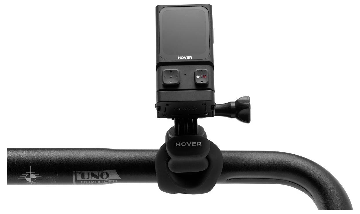 Een kleine zwarte camera gemonteerd op een fietsstuur, gericht naar voren, met het merk 'HOVER' zichtbaar op het apparaat en de bevestiging.