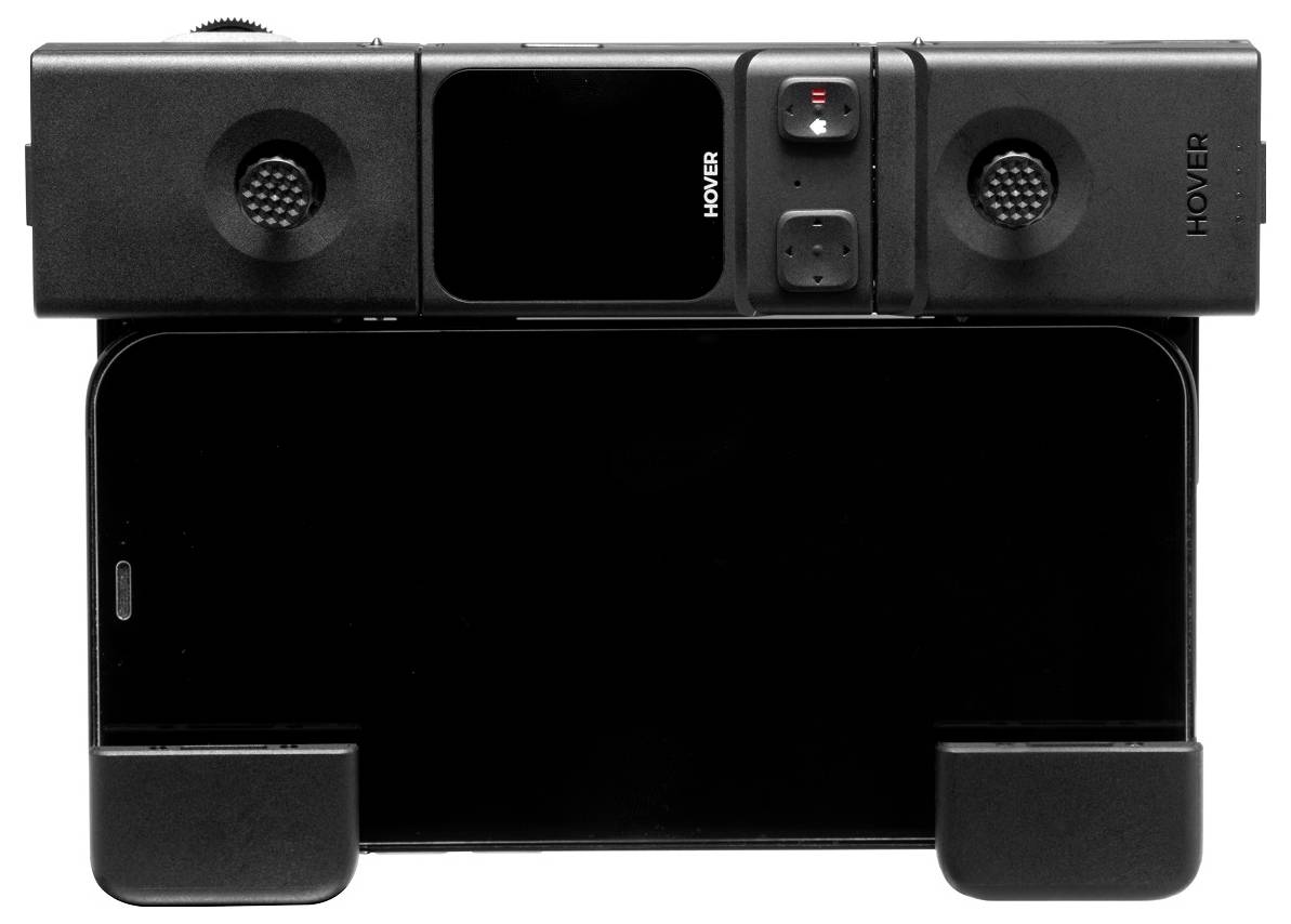 Een rechthoekig zwart apparaat met het label 'HOVER' dat lijkt te zijn ontworpen als een smartphone-accessoire of gamecontroller, bedoeld om een smartphone horizontaal in te plaatsen.