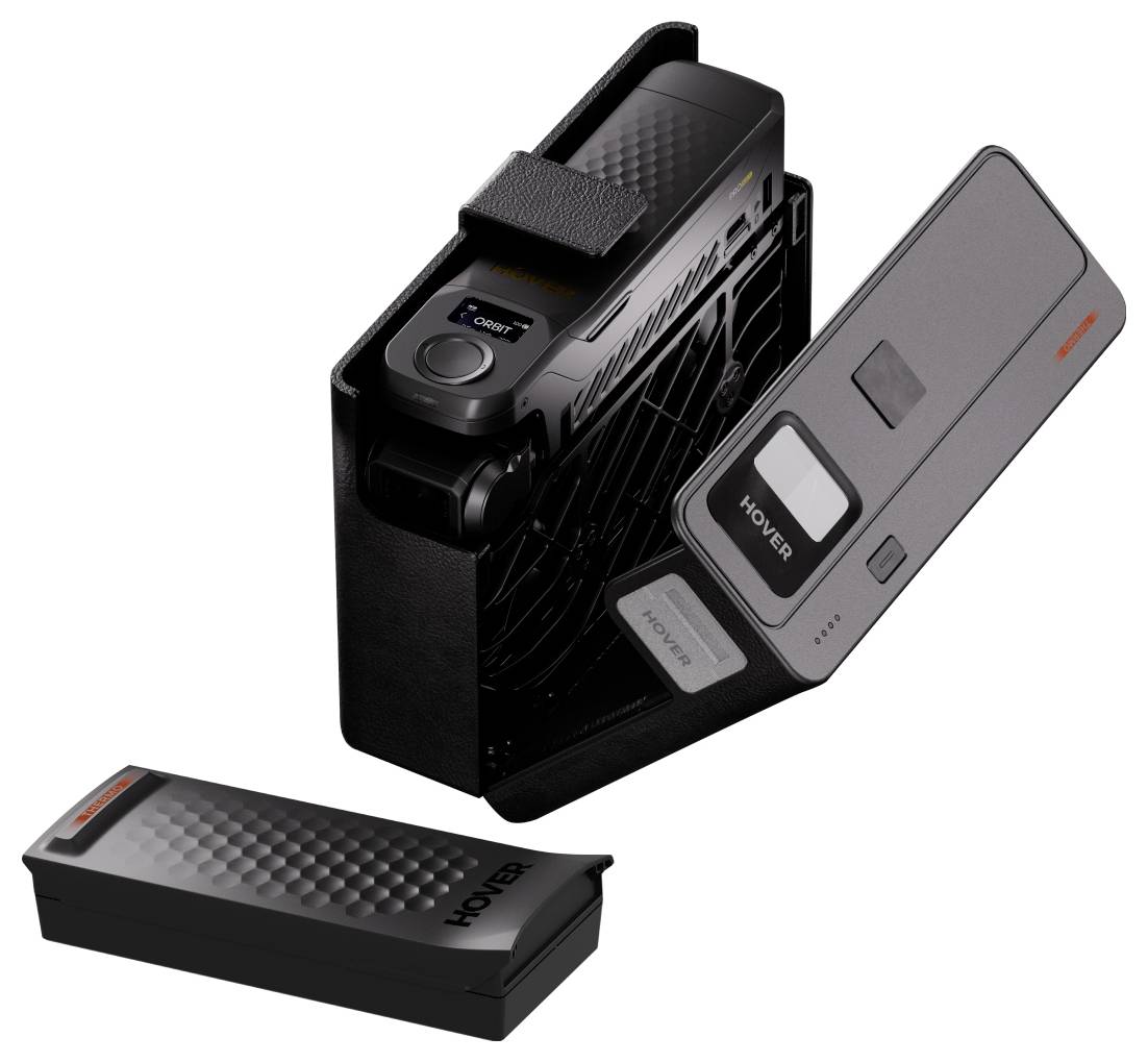 Een vintage zwarte handheld camcorder met een openende compartimentruimte, waarop een batterij met het label 'HOVER' zichtbaar is. Een andere 'HOVER' batterij is ernaast geplaatst.