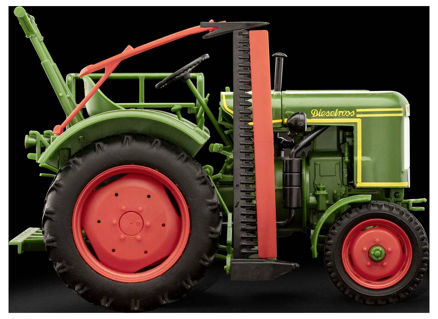 Een vintage groene tractor met rode wielen, gefotografeerd van opzij tegen een zwarte achtergrond. De tractor heeft een verticale oranje streep.