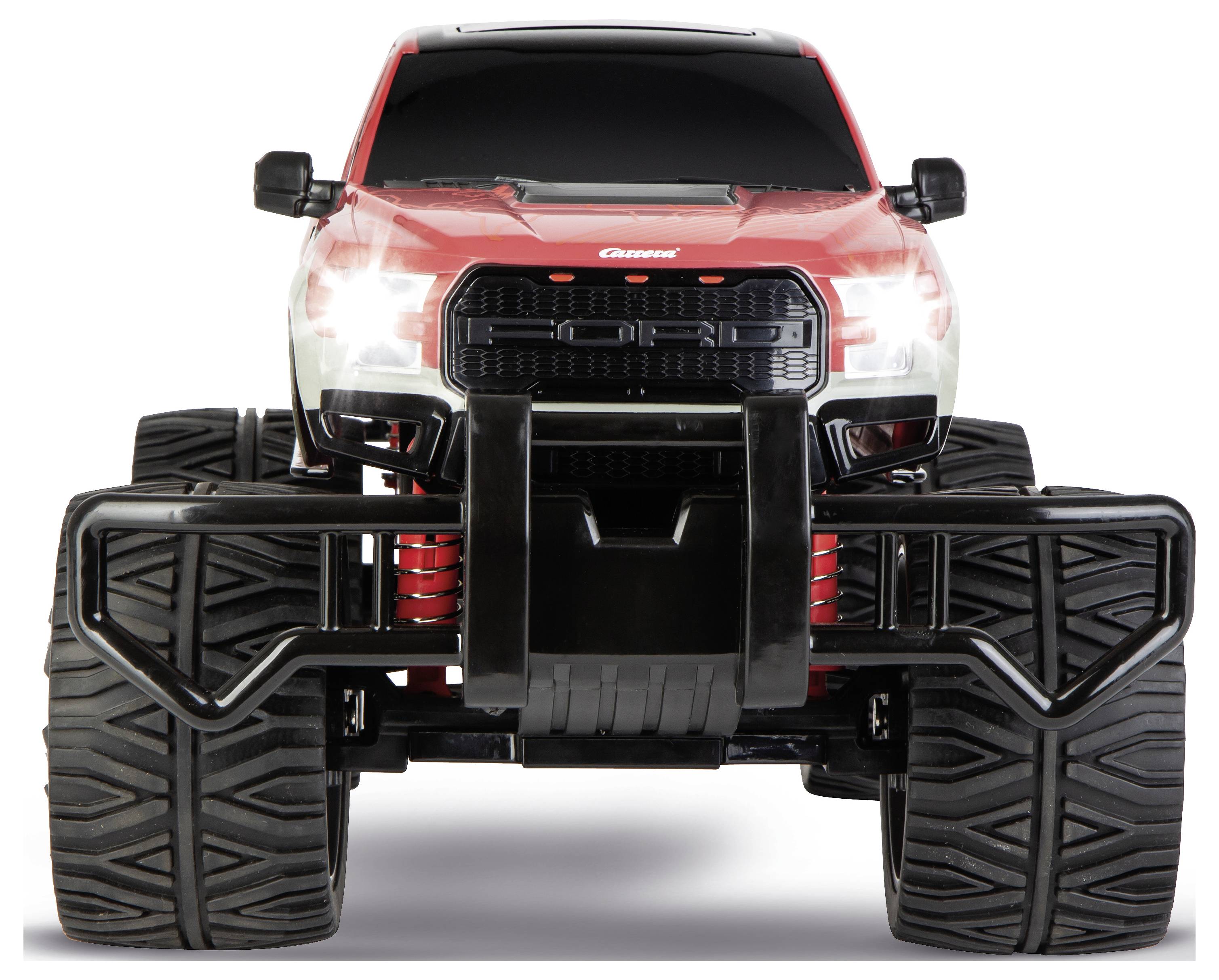 Een rode en zwarte speelgoed monstertruck met grote banden en verhoogde vering, gezien van voren, waarbij de robuuste ontwerpelementen worden benadrukt.
