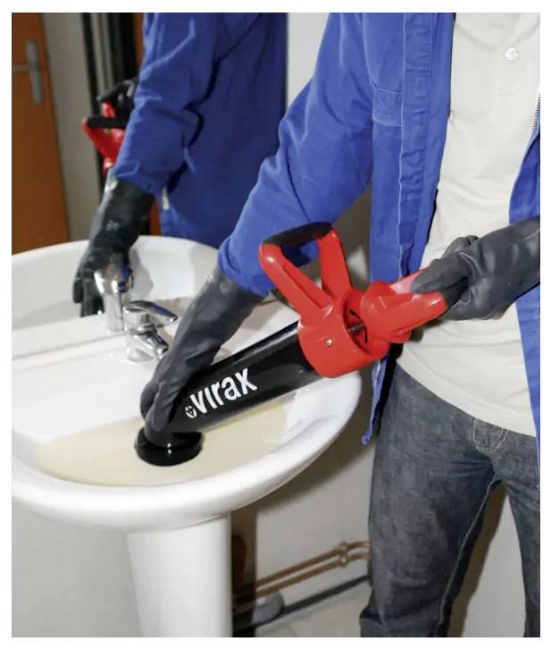 Persoon met handschoenen die een rode buissnijder gebruikt op een zwarte buis onder een wastafel in de badkamer tijdens loodgierswerk.