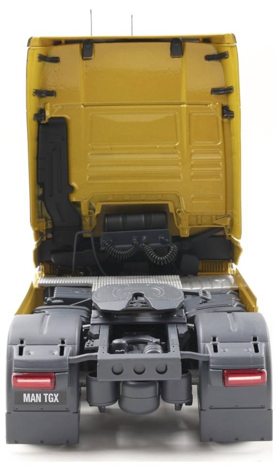 'Gele vrachtwagencabine gezien van achteren met open achterkant, waarbij details van de motorruimte en het aanhangwagenverbindingsgebied zichtbaar zijn.'