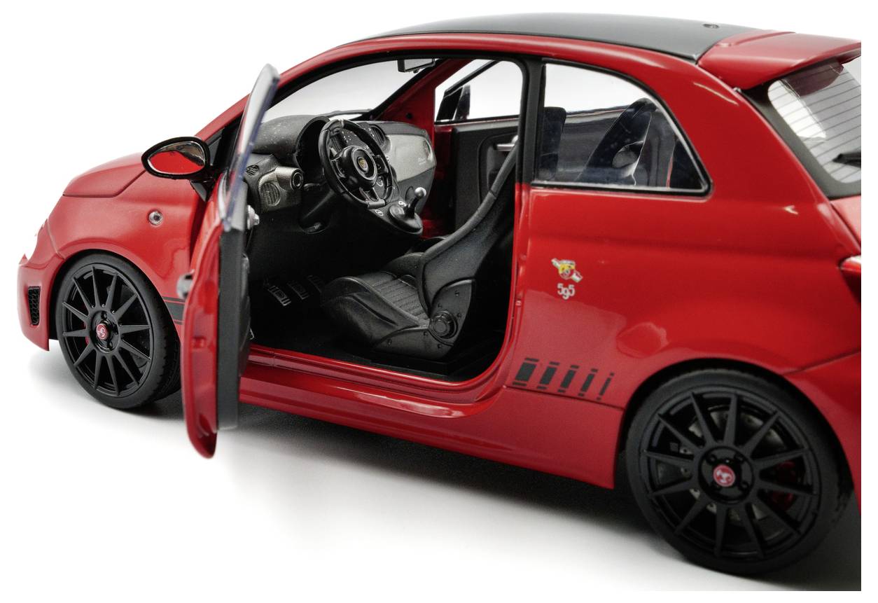 Een rode speelgoedauto met een open portier aan de bestuurderskant, waarbij het zwarte interieur en dashboard zichtbaar zijn. De auto heeft gedetailleerde wielen en sportieve design-elementen.