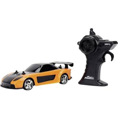 Een oranje en zwarte speelgoed sportwagen met een grote achterspoiler staat naast een zwarte draadloze afstandsbediening met het label 'Fast & Furious.'
