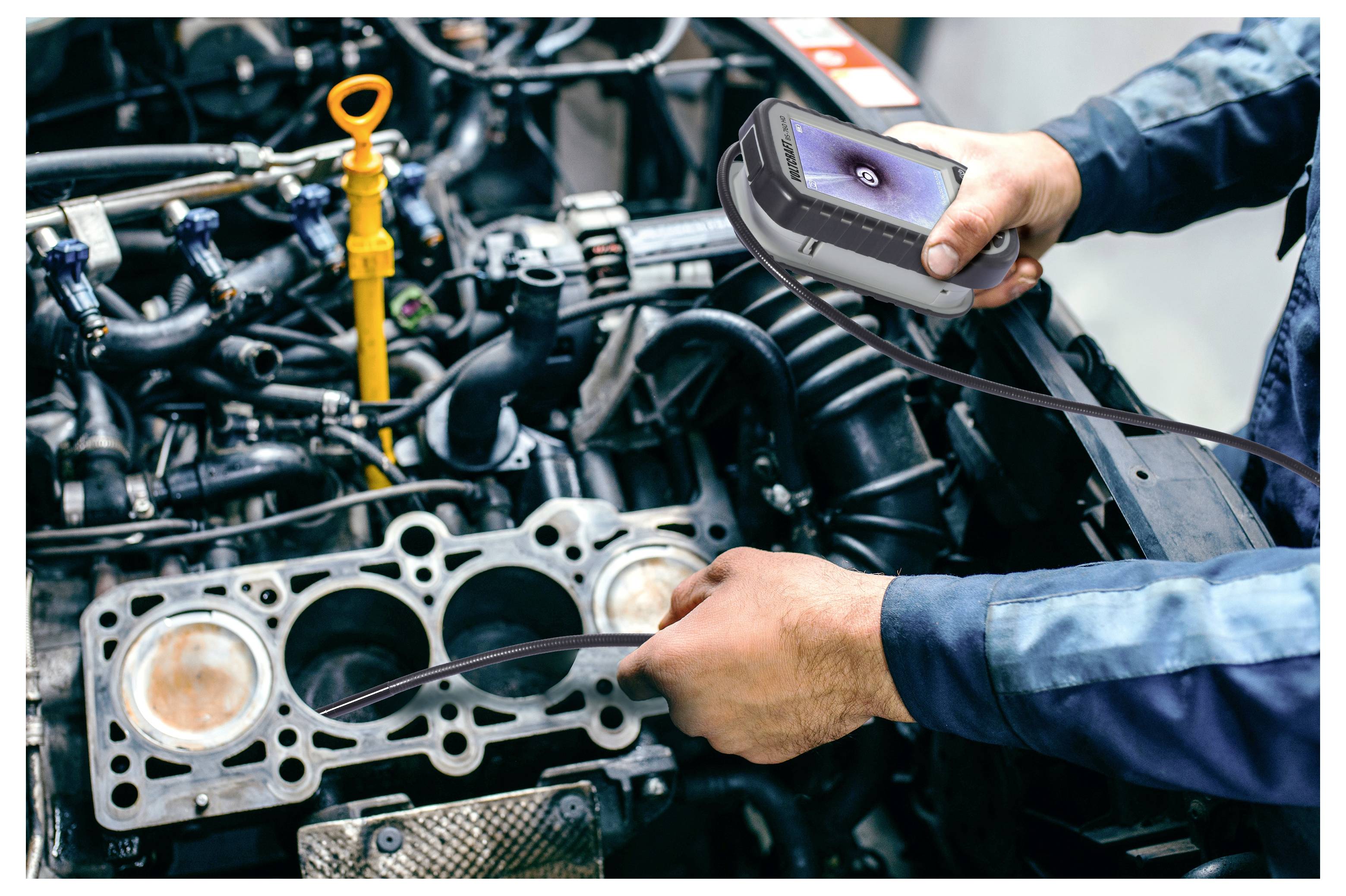 Monteur gebruikt een handheld inspectiecamera om een automotor met verwijderde cilinderkop te onderzoeken en controleert de interne onderdelen.