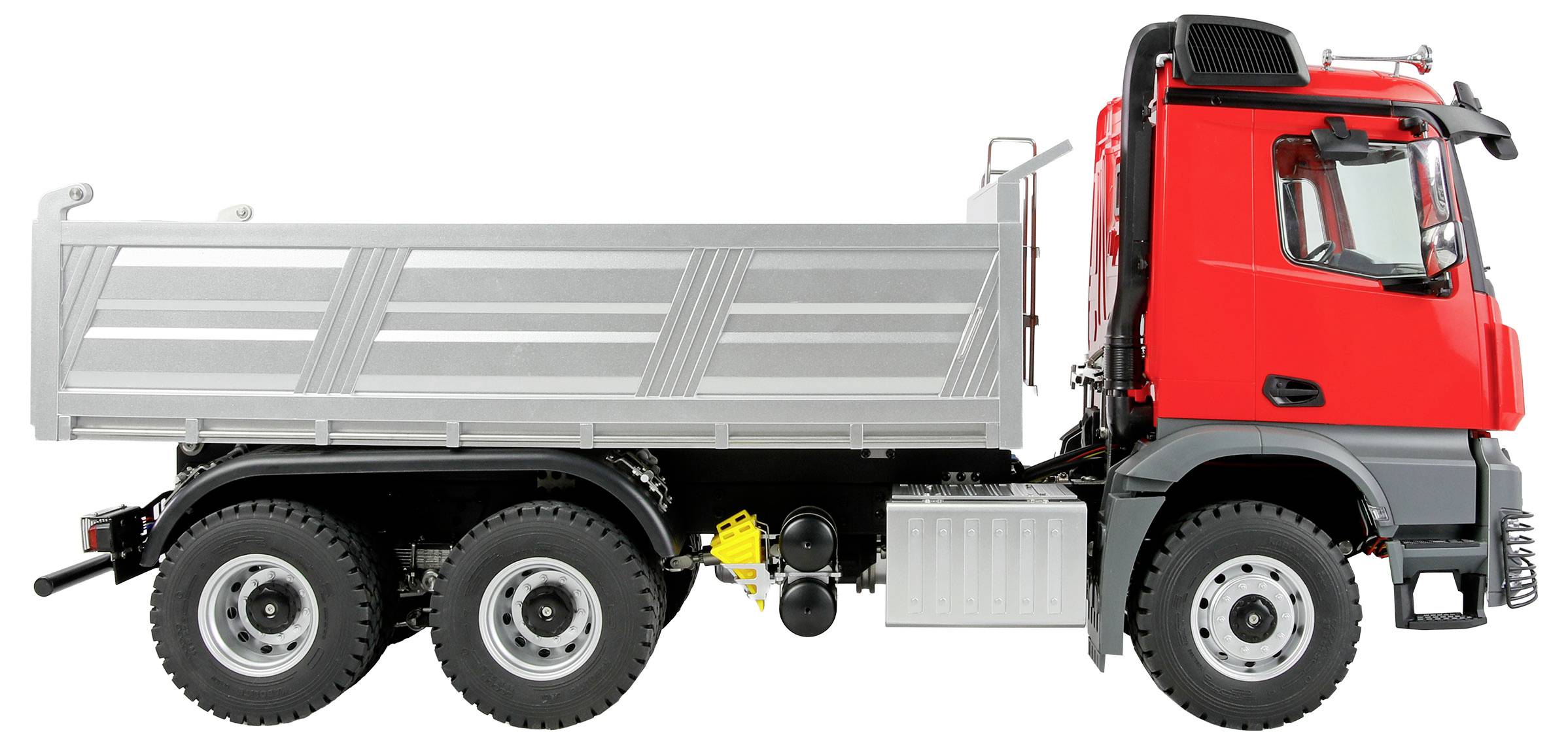 Een rode en zilveren kiepwagen met zes wielen, gezien van opzij, waarbij de bestuurdercabine en de grote laadruimte zichtbaar zijn.