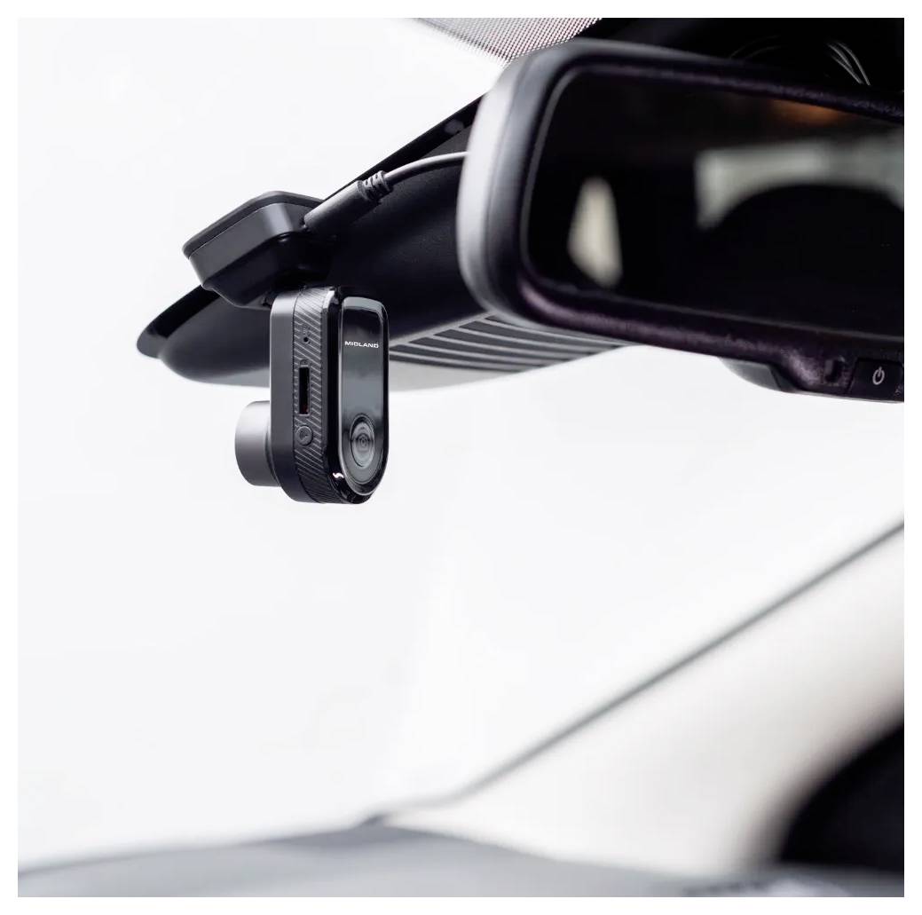 Een compacte zwarte dashcam is gemonteerd achter de binnenspiegel van een auto, gericht naar voren door de voorruit, wat aangeeft dat hij klaarstaat voor gebruik.