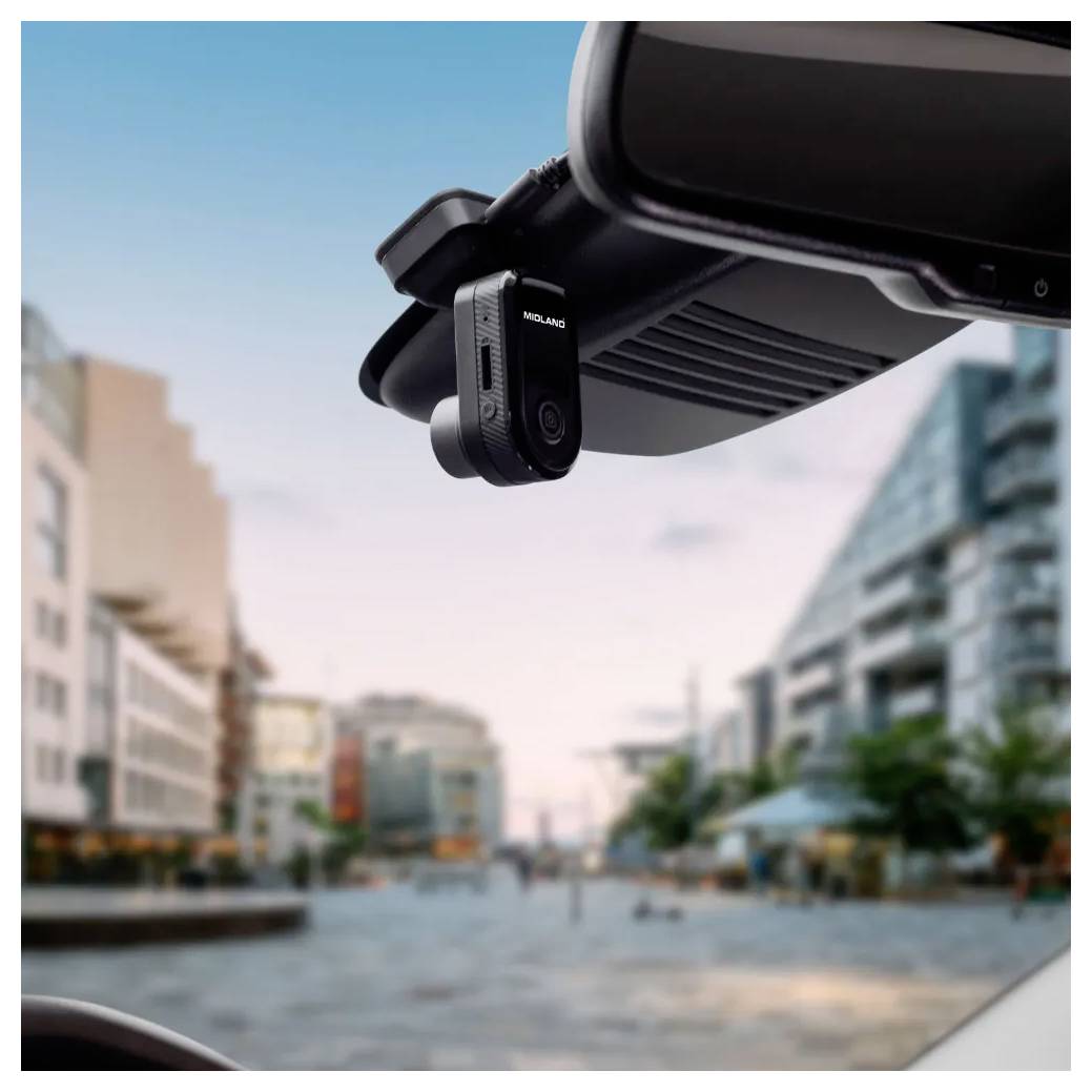 Een kleine dashcam, gemonteerd op de achteruitkijkspiegel van een auto, vangt een uitzicht op van een moderne stadsstraat met gebouwen aan beide zijden.
