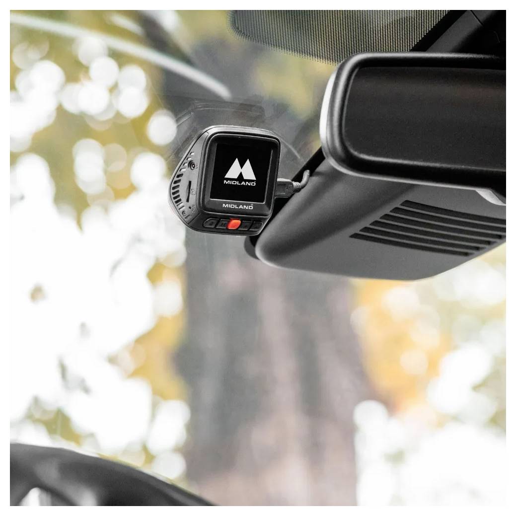Een dashboardcamera bevestigd op de voorruit van een auto, met herfstbladeren vaag op de achtergrond, vangt het zicht vooruit.