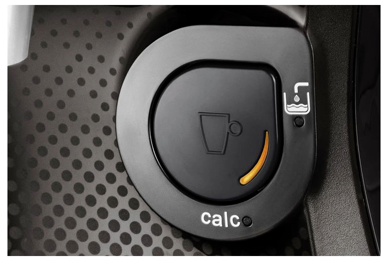 Close-up van een bedieningsknop van een koffiemachine, met een oranje lampje en 'calc' eronder geschreven, wat aangeeft dat ontkalking nodig is.