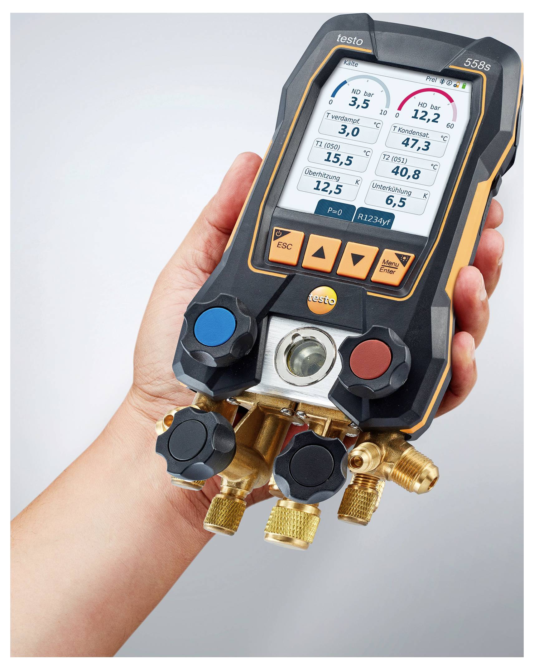 Een hand die een digitale manometer vasthoudt die druk- en temperatuurmetingen weergeeft op een scherm. Zwart en oranje apparaat met verschillende knoppen.