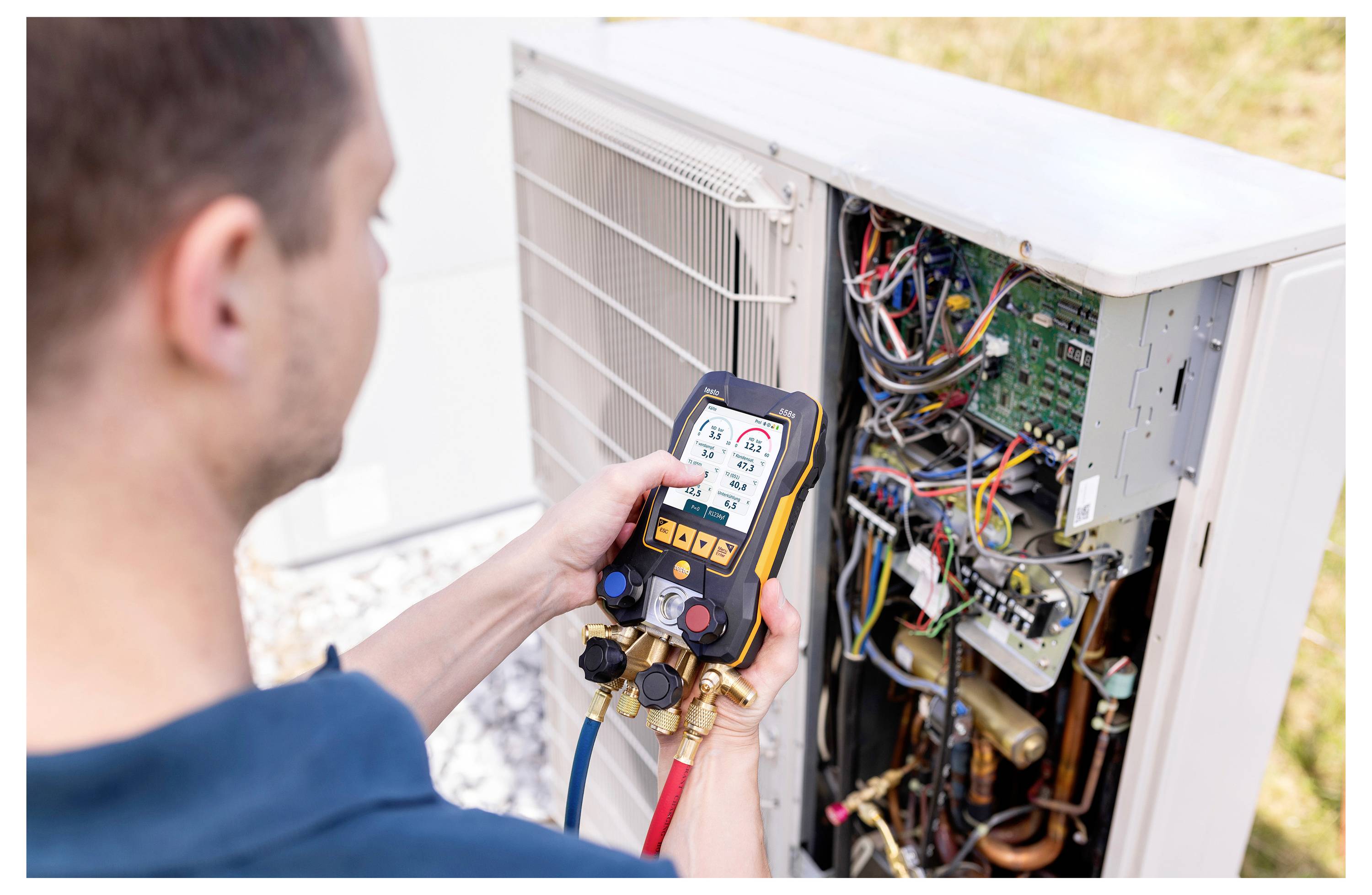 Een technicus gebruikt een digitale meter om de parameters van een buitenopstellingsunit van een airconditioning te controleren, waarbij zichtbare draden en printplaten te zien zijn.