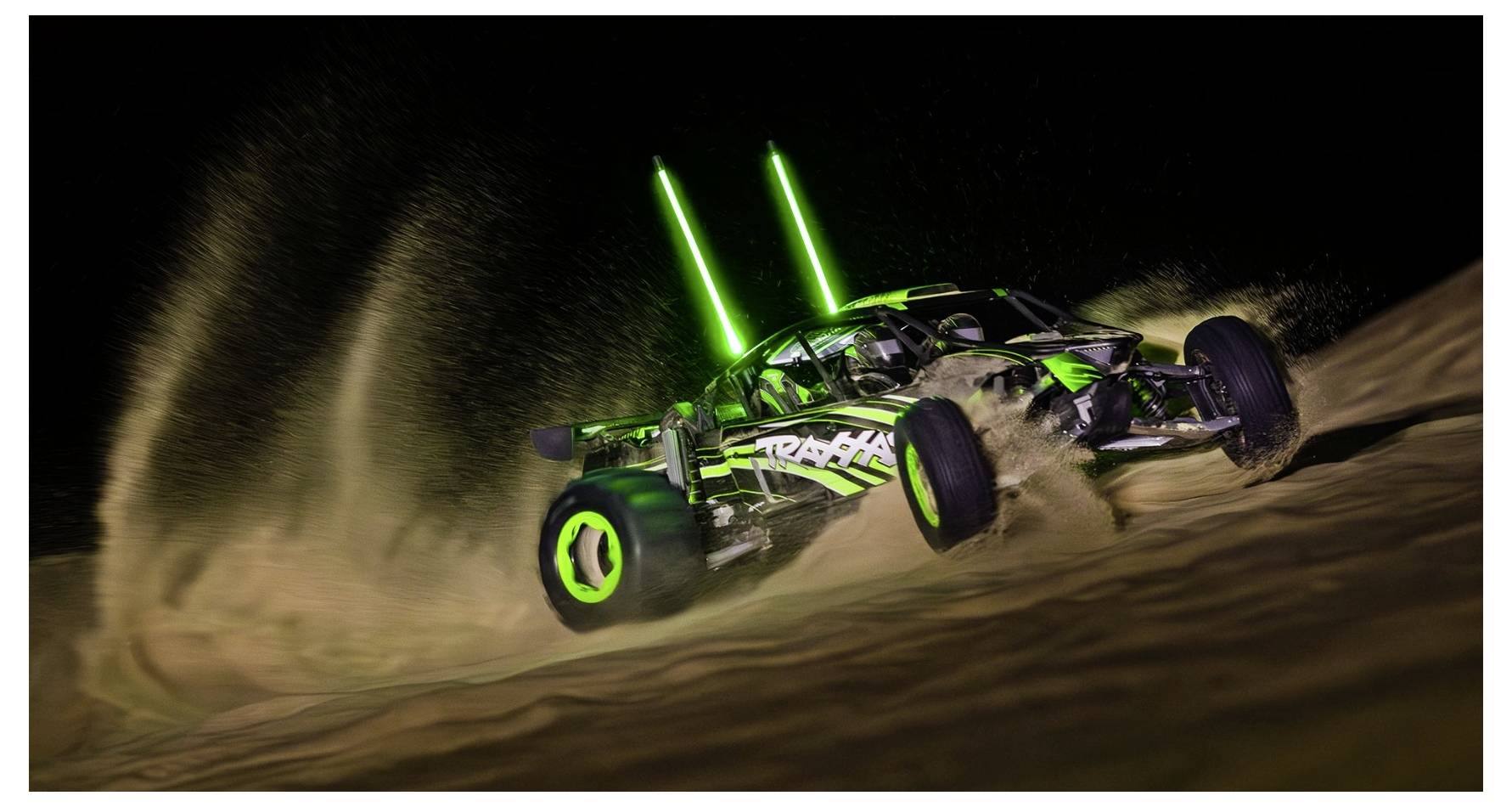 Een afstandsbediende strandbuggy met neongroene lichten scheurt 's nachts over zanderig terrein en werpt een spectaculaire stofwolk op.