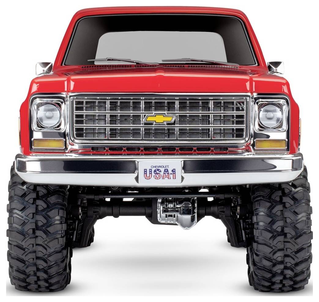 'Vooraanzicht van een opgetilde rode vintage truck met grote banden en een chromen grille, voorzien van een Chevrolet-embleem en een USA1-kentekenplaat.'