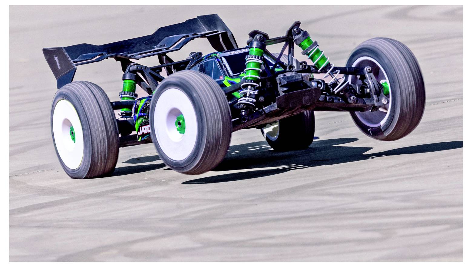 Een afstandsbediende auto racet over een circuit, waarbij de groene schokdempers en aerodynamische vormgeving zichtbaar zijn tijdens een bocht.