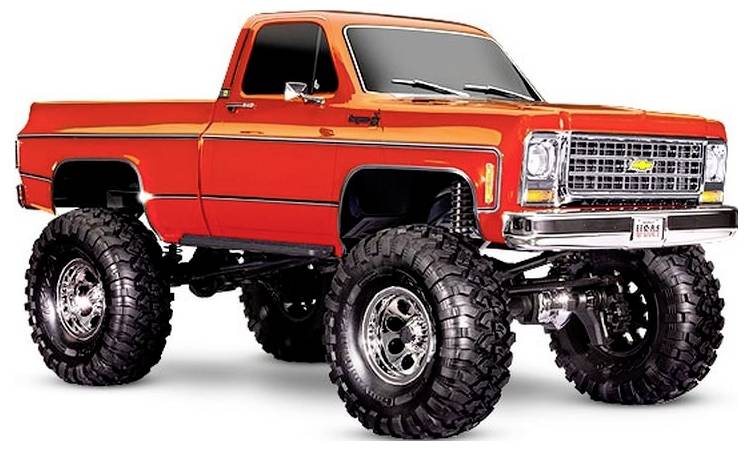 Een oranje klassieke pickup truck met grote, terreinbanden en een verhoogde ophanging, die zijn robuuste en gemodificeerde uitstraling benadrukt.