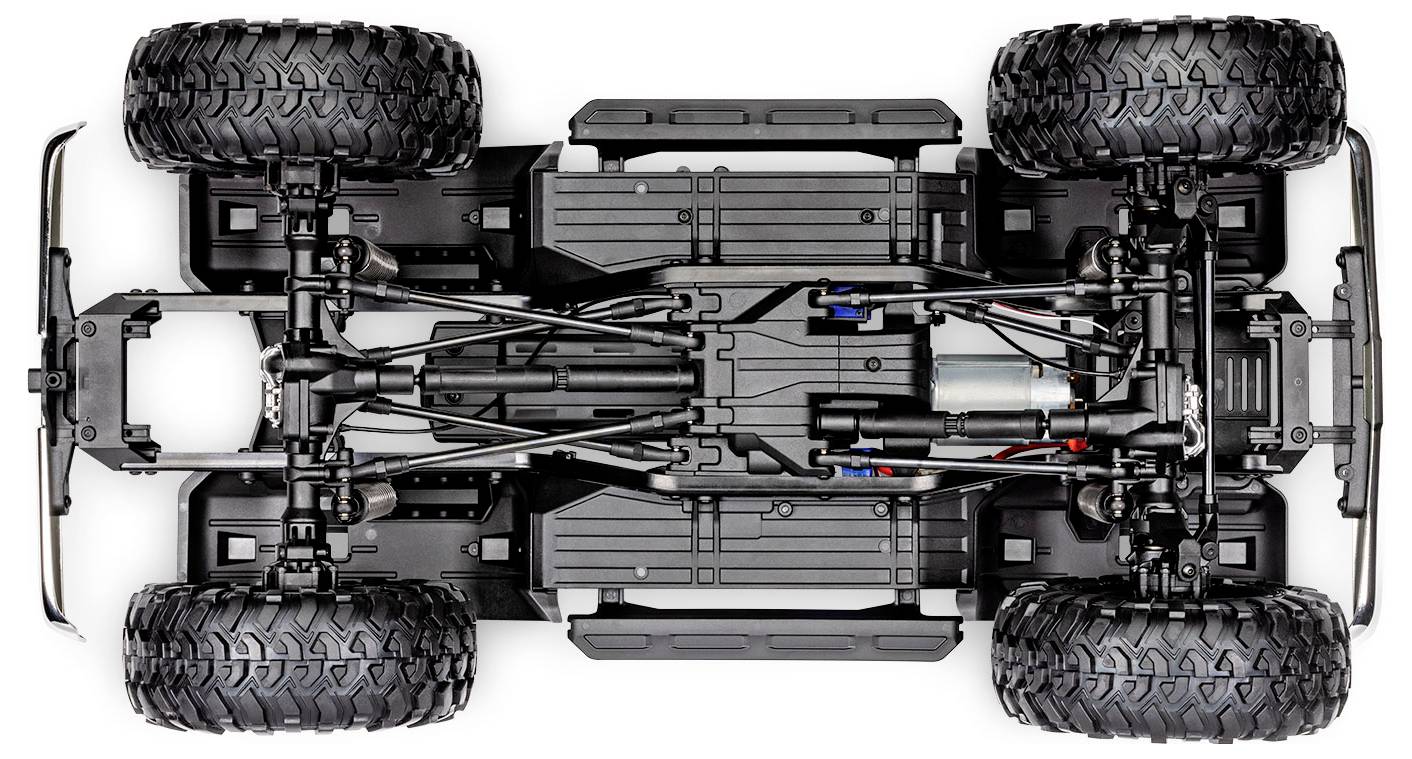 Onderaanzicht van een chassis van een bestuurbare auto met grote banden, waarop de ophanging, motor en aandrijfcomponenten zichtbaar zijn.