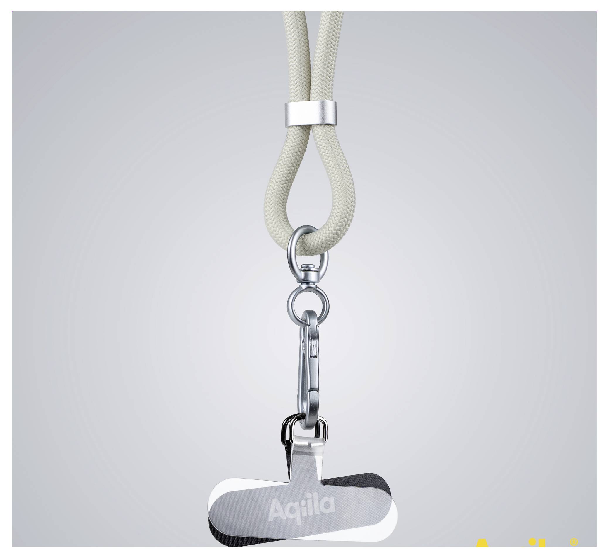 Een metalen sleutelhanger met het woord 'Aqila' gegraveerd op een zilveren naamplaatje, bevestigd aan een beige lus koord met een metalen sluiting.