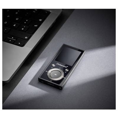 Een zwarte Intenso MP3-speler met een rond bedieningsvlak rust op een grijze ondergrond nabij een laptoptoetsenbord, verlicht door een lichtstraal.