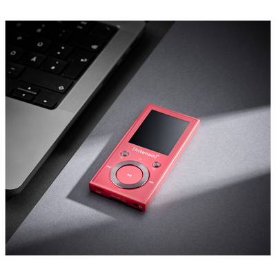 Een rode MP3-speler met het label 'Intenso' rust op een donker oppervlak naast een laptoptoetsenbord, verlicht door een zacht licht.
