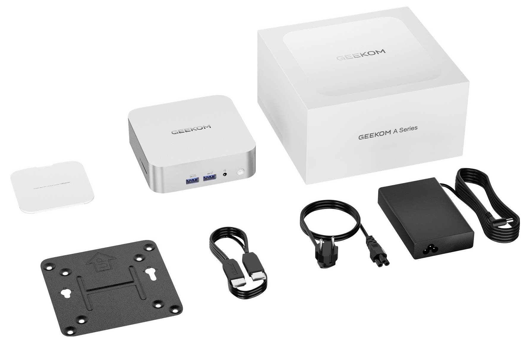 Compact computersysteem met poorten, stroomadapter, kabels, VESA-beugel en verpakking. De merknaam is zichtbaar op de apparaten.