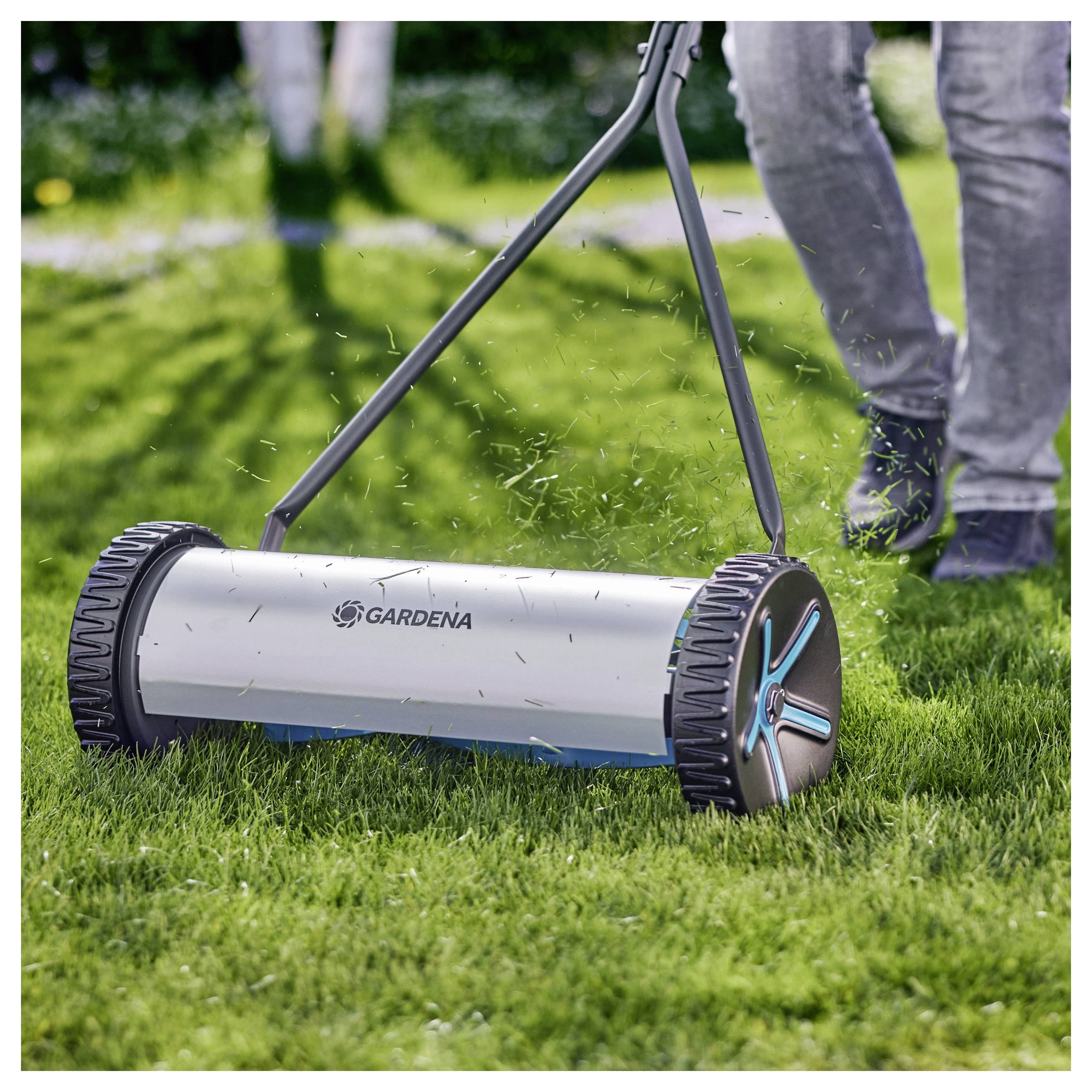 Handmatige grasmaaier die door een persoon over weelderig gras wordt voortgeduwd, met aandacht voor het moderne ontwerp en de functionaliteit van de maaier.