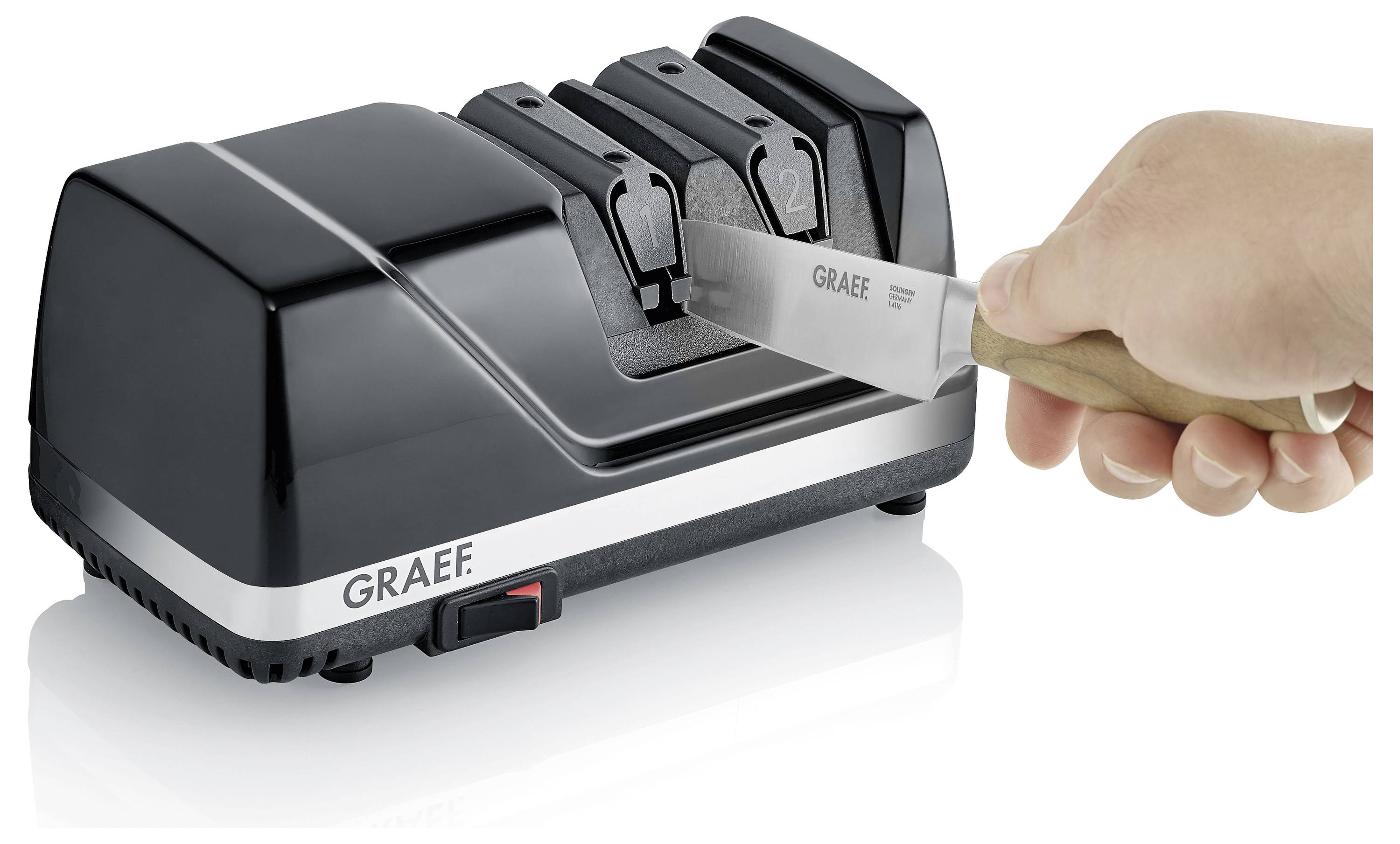 Een hand scherpt een mes met een zwarte Graef elektrische messenslijper met twee sleuven genummerd '1' en '2'.
