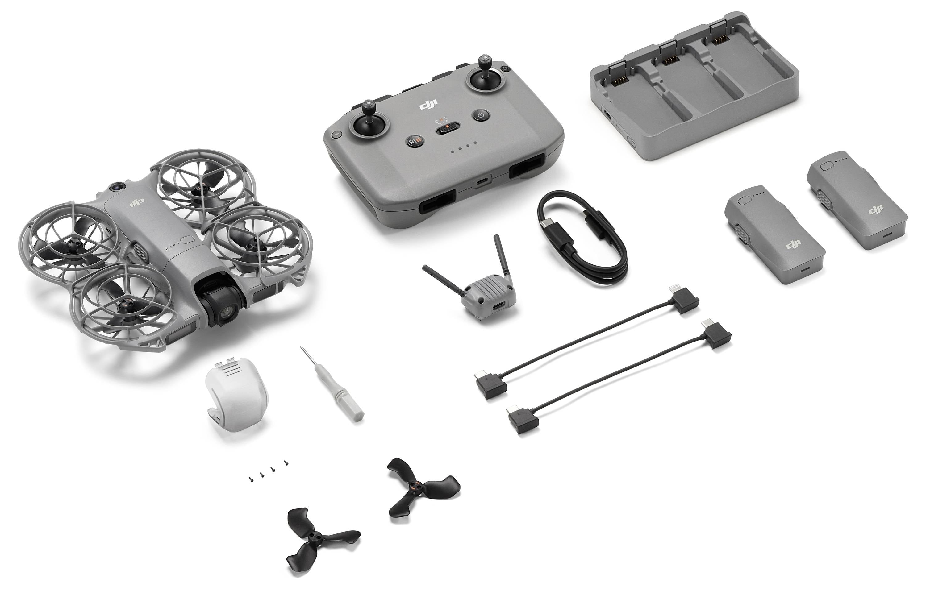 Drone-kit met controller, twee sets propellers, batterij-laadstation, twee batterijen, schroevendraaier, schroeven, kabels en adapter.